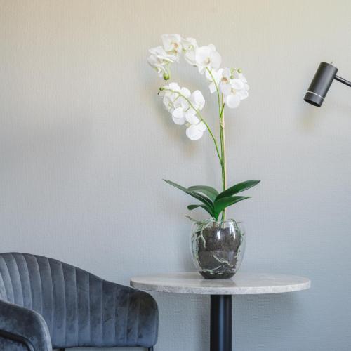 a vase with white flowers on a table next to a lamp at VICI Hotels Linköping in Linköping