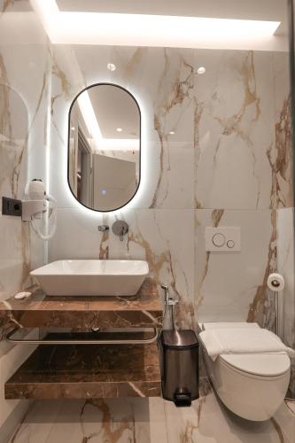 a bathroom with a sink and a toilet and a mirror at Hotel Oasis in Sarandë