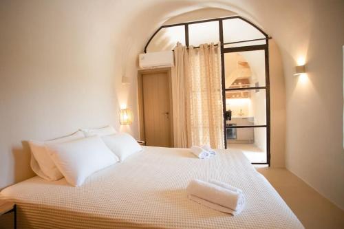 a bedroom with a white bed with a window at ΠΥΡΓΟΣ ΜΠΕΧΡΑΚΗ-Μάνη in Pirgos Dhirou