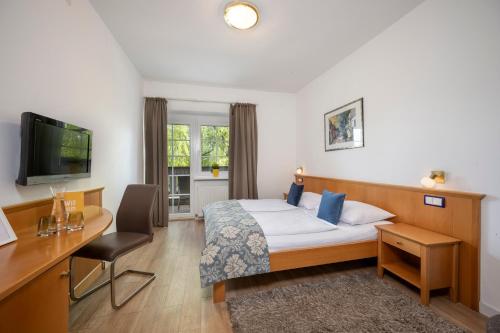 ein Hotelzimmer mit einem Bett, einem Schreibtisch und einem TV in der Unterkunft Salzburg Hotel Lilienhof in Salzburg