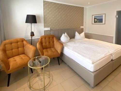 ザスニッツにあるホテル ツム ハーフェンのベッド1台と椅子2脚が備わるホテルルームです。
