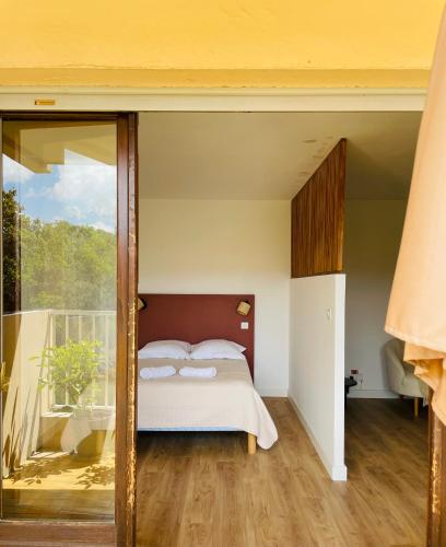 a bedroom with a bed and a balcony at Appartement l'orée du bois Ajaccio in Ajaccio