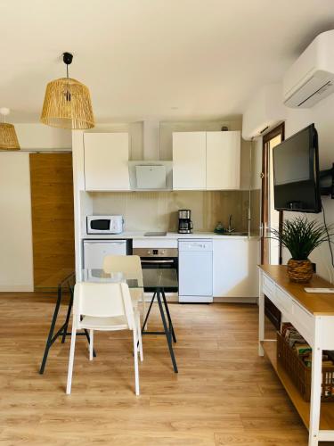 une cuisine avec des armoires blanches et une table et des chaises dans l'établissement Appartement l'orée du bois Ajaccio, à Ajaccio