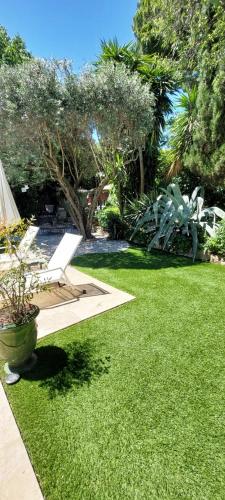 a yard with a lawn with a chair and trees at l appentis du chai in Roujan