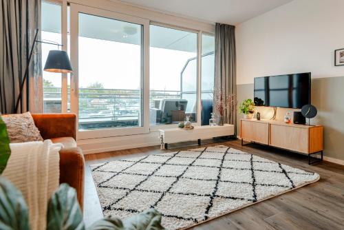 a living room with a couch and a large window at Kaag Resort in Warmond