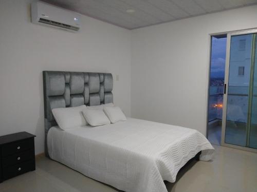 - une chambre blanche avec un grand lit et une fenêtre dans l'établissement Lujoso Penthouse, à Buenaventura