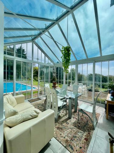 a conservatory with a couch and a table and chairs at TORWOOD VICTORIAN HOUSE in Ventnor