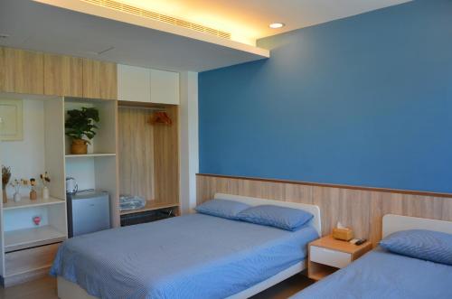 1 dormitorio con 2 camas y pared azul en Blowing in the wind Homestay, en Jincheng
