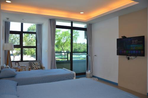 1 dormitorio con 2 camas, TV y ventana en Blowing in the wind Homestay, en Jincheng
