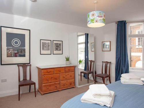 a bedroom with a bed and two chairs and a dresser at 2 Central, spacious, apartment with private patio in Sidmouth