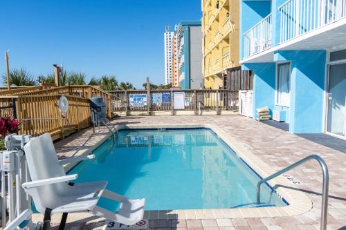 a swimming pool with a deck and a chair and a building at Beach Club at Montego Inn in Myrtle Beach