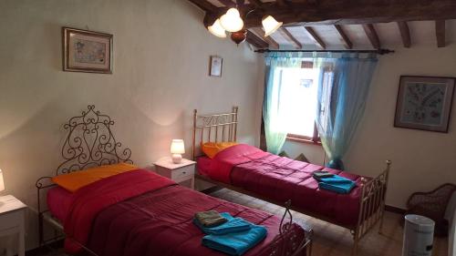 two beds sitting in a room with a window at la casina della bubbolina in Semproniano