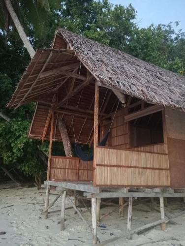 a house with a thatched roof on the beach at Nyande Rengkri Guest House in Kri