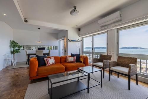 a living room with an orange couch and chairs at Unique Riverview Apartment in Cruz Quebrada