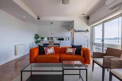 an orange couch in a living room with a table at Unique Riverview Apartment in Cruz Quebrada