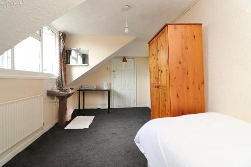 1 dormitorio con 1 cama y armario de madera en Pebbles Guest House en Southampton