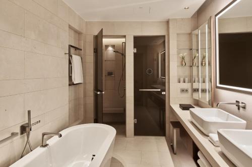 La salle de bains est pourvue d'une baignoire, de 2 lavabos et d'une douche. dans l'établissement The Fontenay Hamburg, à Hambourg
