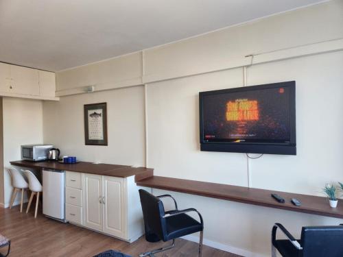 a room with a television on a wall with chairs at Buena Vista in San Carlos de Bariloche