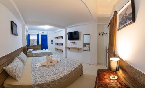 a small room with two beds and a tv at Pousada Nativos Lençois in Lençóis