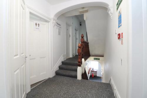 a hallway with a staircase with white walls and a door at Pebbles Guest House in Southampton