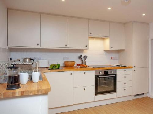 a kitchen with white cabinets and a wooden counter top at 1 Perfectly located stylish, comfortable apartment in Sidmouth
