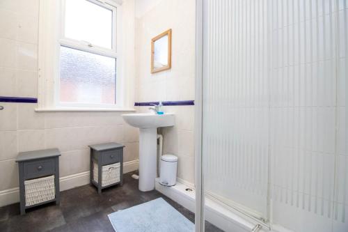 a white bathroom with a sink and a shower at Pebbles Guest House in Southampton