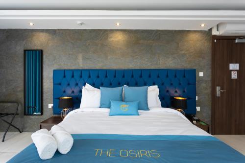 a large bed with a blue headboard and white pillows at THE OSiRiS in Marsaxlokk