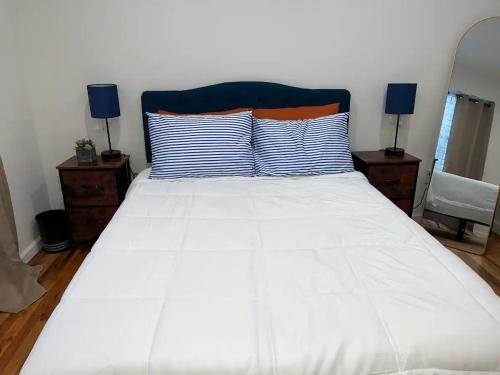 a white bed with blue and orange pillows on it at Harmony in the Heights - BR 1 in Newark