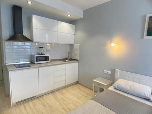 Una cocina con gabinetes blancos y una cama en una habitación. en Premium palace apartments, en Batumi