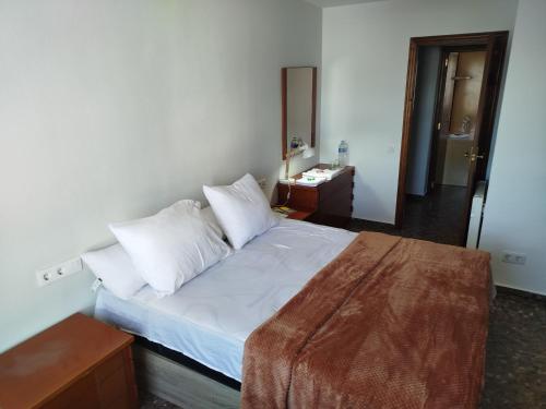 1 dormitorio con 1 cama con sábanas y almohadas blancas en ushuaia, en Castellón de la Plana