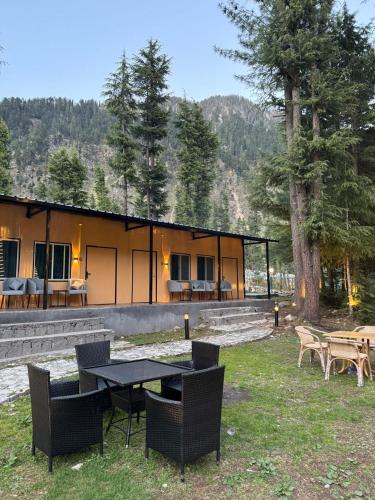 a house with a table and chairs in the yard at Infinity Villa and Resort Kumrat Valley in Tāl