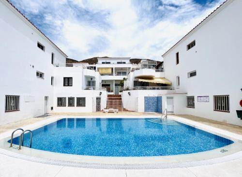 una casa con piscina delante de un edificio en Sunshine Luxury View Los Cristianos, en Los Cristianos