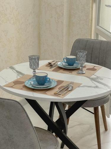a table with two cups and saucers on it at K7 Family 1комнатная квартира in Atyraū