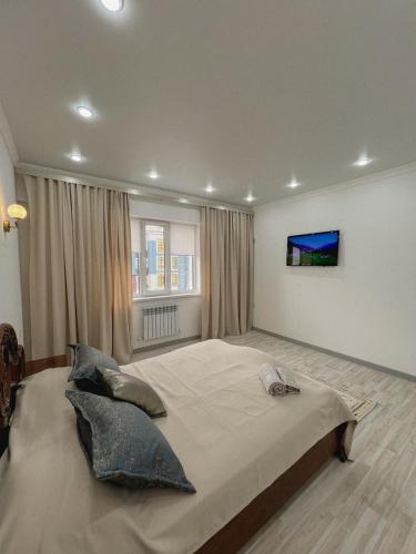 a bedroom with a large bed with a tv on the wall at K7 Family 1комнатная квартира in Atyraū