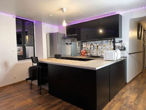 une cuisine avec des armoires noires et un comptoir dans l'établissement Duplex Corbeil-Essonne, à Corbeil-Essonnes