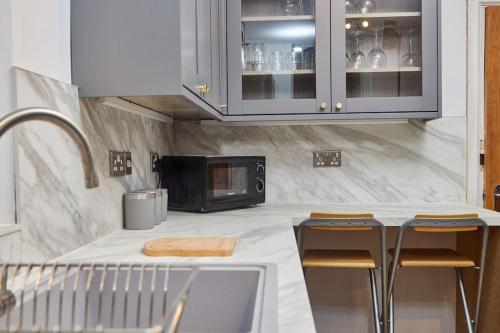 a kitchen with a counter with stools and a microwave at Flat 5 Minutes From The Beach - Street Parking in Whitley Bay