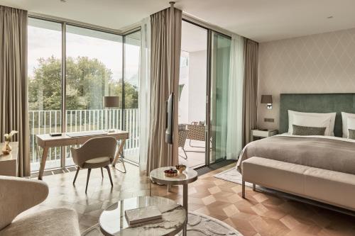 a hotel room with a bed and a desk and a balcony at The Fontenay Hamburg in Hamburg