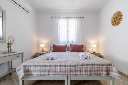 a white bedroom with a bed with towels on it at Aelia Apartment in Skopelos Town
