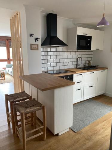 a kitchen with white cabinets and a kitchen island with stools at Rincón de Beluso, Bueu in Pontevedra