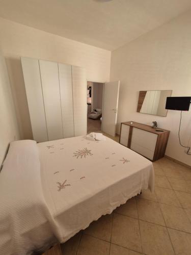 um quarto com uma cama branca e uma mesa em LaCasaDiVito em Marsala