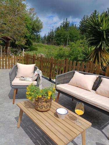 a patio with two couches and a table with a wine glass at Belaustegi turismo rural in Ispáster