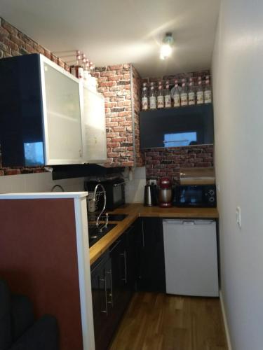 Elle comprend une petite cuisine avec des placards blancs et un mur en briques. dans l'établissement Appartement 27 m2 et parking, à Rennes