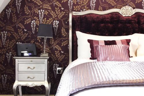 a bedroom with a bed and a night stand with a lamp at The Six Bells in Bourne