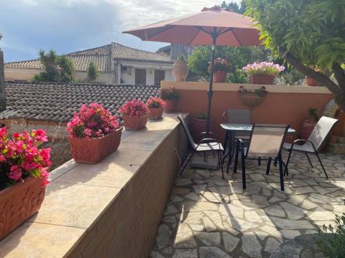 a patio with a table and chairs and an umbrella at Lori House in Corfu. Feel like your home in Skriperón