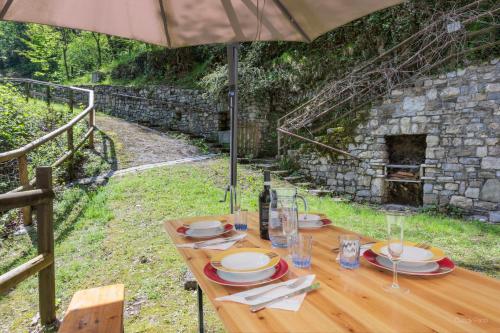 a wooden table with an umbrella in front of a stone wall at Antico Mulino Baderem in Sorisole