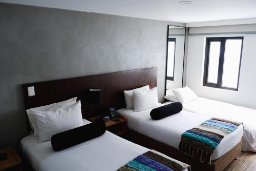 a hotel room with two beds and two windows at Hotel DC Feria in Bogotá
