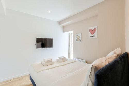 Cette chambre blanche dispose d'un lit et d'une télévision. dans l'établissement Charme Parisien 4 Personnes, 1 chambre, 19ème, à Paris