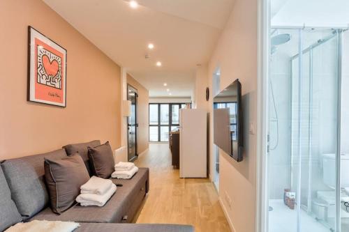 - un salon avec un canapé et un mur en verre dans l'établissement Charme Parisien 4 Personnes, 1 chambre, 19ème, à Paris