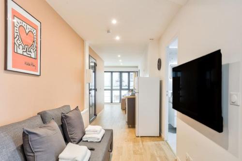 un salon avec un canapé et une télévision à écran plat dans l'établissement Charme Parisien 4 Personnes, 1 chambre, 19ème, à Paris