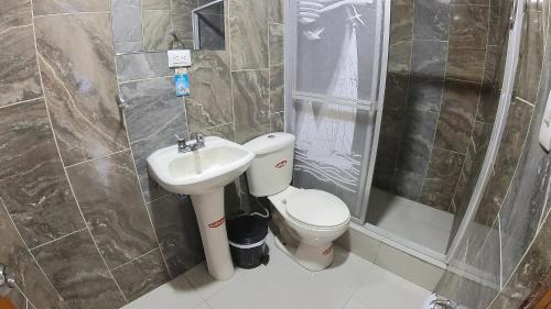 a bathroom with a toilet and a sink and a shower at Hostal Flor de los Ángeles in Guamote